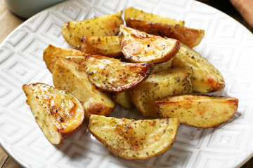 Baked spicy potatoes on white plate, closeup