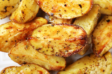 Baked spicy potatoes on white plate, closeup