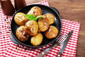 Baked potatoes in pan on wooden table, top view