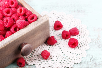 Fresh raspberries in wooden chest on table, closeup