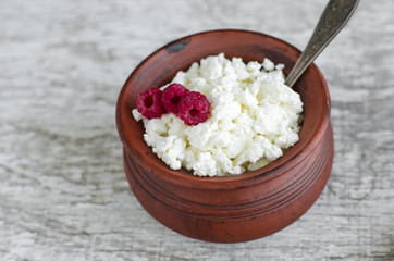 Crumbly homemade cottage cheese in a clay pot