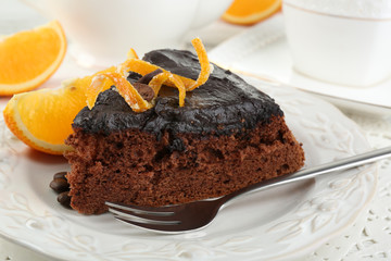 Piece of Chocolate cake and orange on plate, on table  background