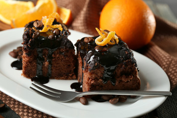 Fototapeta na wymiar Portion of Cake with Chocolate Glaze and orange on plate, on wooden background