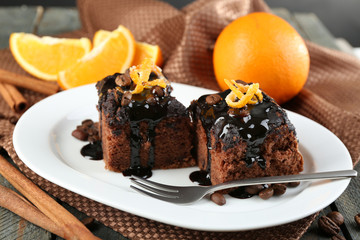Portion of Cake with Chocolate Glaze and orange on plate, on wooden background