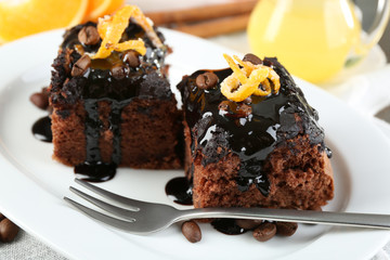 Portion of Cake with Chocolate Glaze and orange on plate, on wooden background