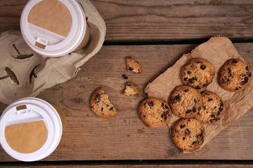 Paper cups of coffee with cookies on wooden table close up