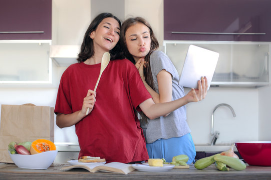 Two young women taking a selfie while cooking in the kitchen