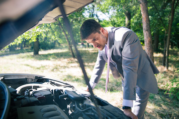 Man looking under the hood of car
