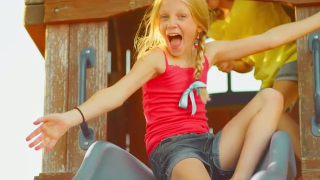 Young blonde girls on a slide outside