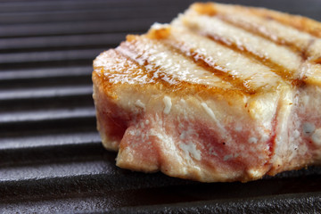 Grilled tuna steak on black cast iron griddle closeup