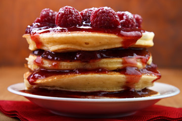 Warm baked pancakes with strawberry jam and fresh raspberry fruits on white plate