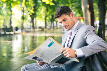 Businessman reading newspaper outdoors