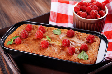 Fresh pie with raspberry in pan on wooden table, closeup