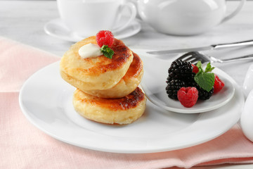 Fritters of cottage cheese with berries in plate on table, closeup