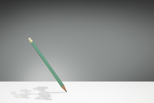 Green wooden pencil with a tree shaped shadow