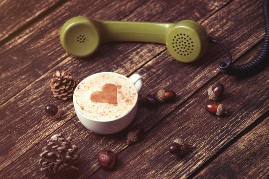 Cup of coffee with heart shape and green handset