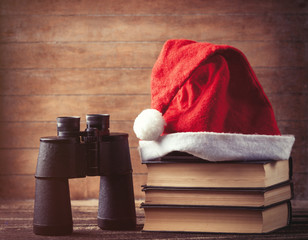 Obraz na płótnie Canvas Santas hat over books near black binocular
