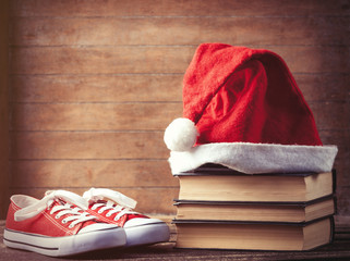 Obraz na płótnie Canvas Santas hat over books near red gumshoes