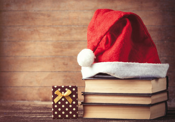 Obraz na płótnie Canvas Santas hat over books near gift box