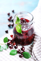Jar of gooseberry jam on wooden table close-up