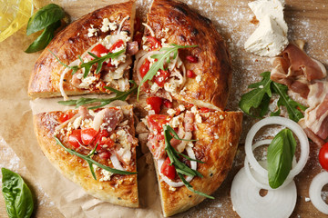 Greek homemade pizza with ham,onion, roasted tomato, creamy feta on wooden table background