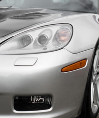 Close-up view of silver sports car headlight.