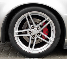 Silver sports car wheel on the road.