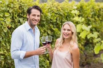 Young happy man smiling at camera and holding a glass of wine