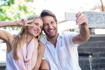Naklejka premium Smiling couple sitting and taking selfies