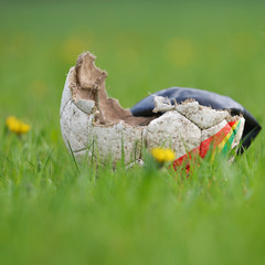 Fußball liegt kaputt auf der grünen Wiese