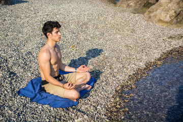 Young Man Meditating or Doing Yoga Exercise by Sea