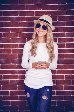 Gorgeous smiling blonde hipster holding smartphone