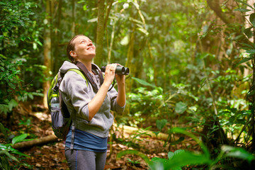 Hiker watching through binoculars wild birds in the jungle. - 87900303