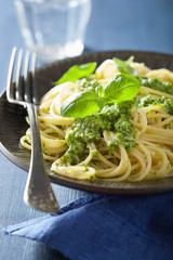 spaghetti pasta with pesto sauce over blue