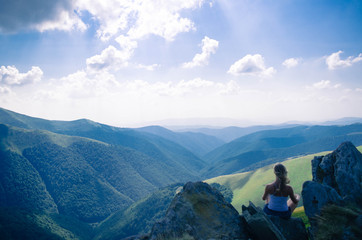 Naklejka premium Young blond woman meditating in the beautiful mountain landscape