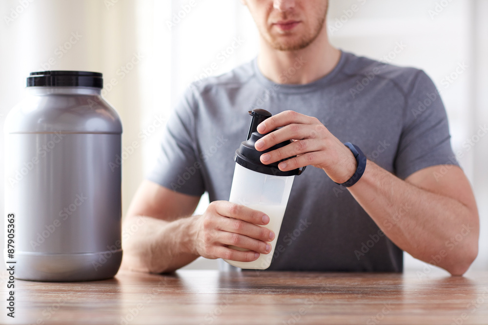 Wall mural close up of man with protein shake bottle and jar