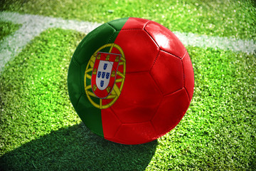 Plakat football ball with the national flag of portugal lies on the green field near the white line