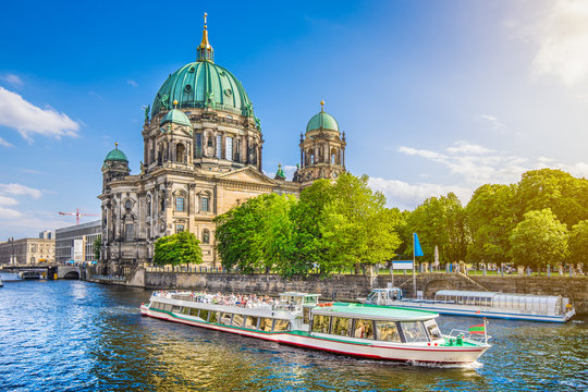 Famous Berlin Cathedral at Museumsinsel with excursion boat on Spree river at sunset, Berlin, Germany