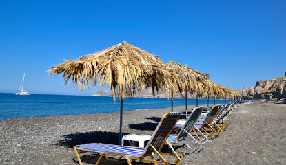 Sea beach with umbrellas and empty seats in Santorini