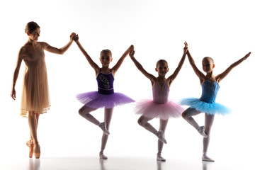 Three little ballerinas dancing with personal ballet teacher in