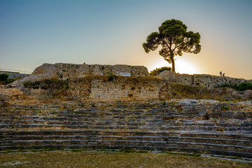 Pine stands on old city wall with sunset in the background Theaterruine in Pula