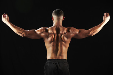 Fototapeta na wymiar Male bodybuilder flexing muscles, back view