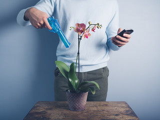 Man watering orchid with water pistol