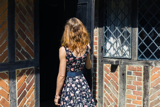 Young woman opening door and entering old building