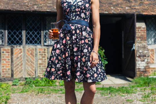 Young woman outside country house with drink in her hand