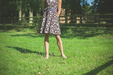 Young woman standing in field by fence on summer day