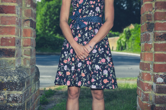 Young woman in dress standing by wall outside