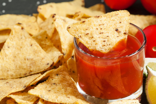 Nachos, tomato sauce, tomatoes, salt, lime on  dark stone backgr