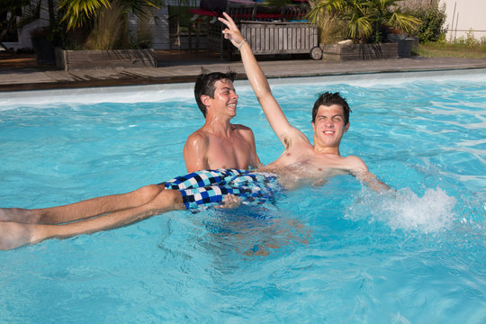 Portrait of two teenager splashing water together in pool
