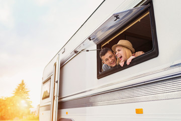 Young couple sitting in a camper van - obrazy, fototapety, plakaty